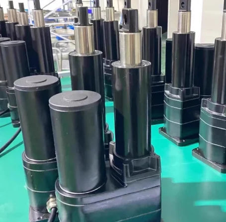Row of cylindrical black mechanical components on a green surface